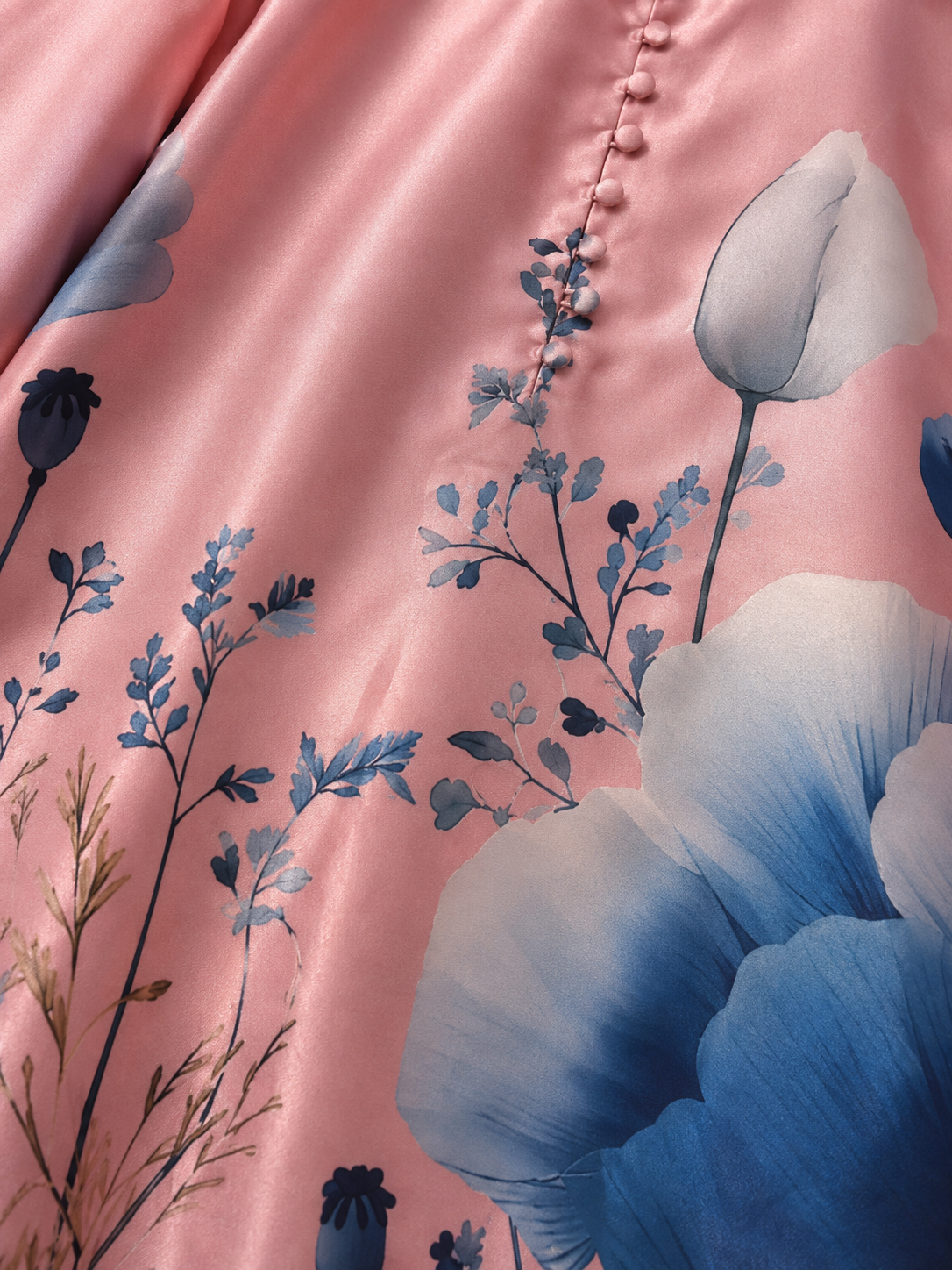 Close-up of blush pink fabric with blue floral print and covered buttons