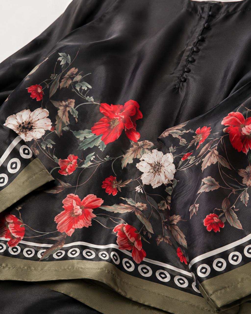 Close-up of the black satin-look floral fabric, decorative border and covered buttons of the BACTRA Gulzar Noir suit
