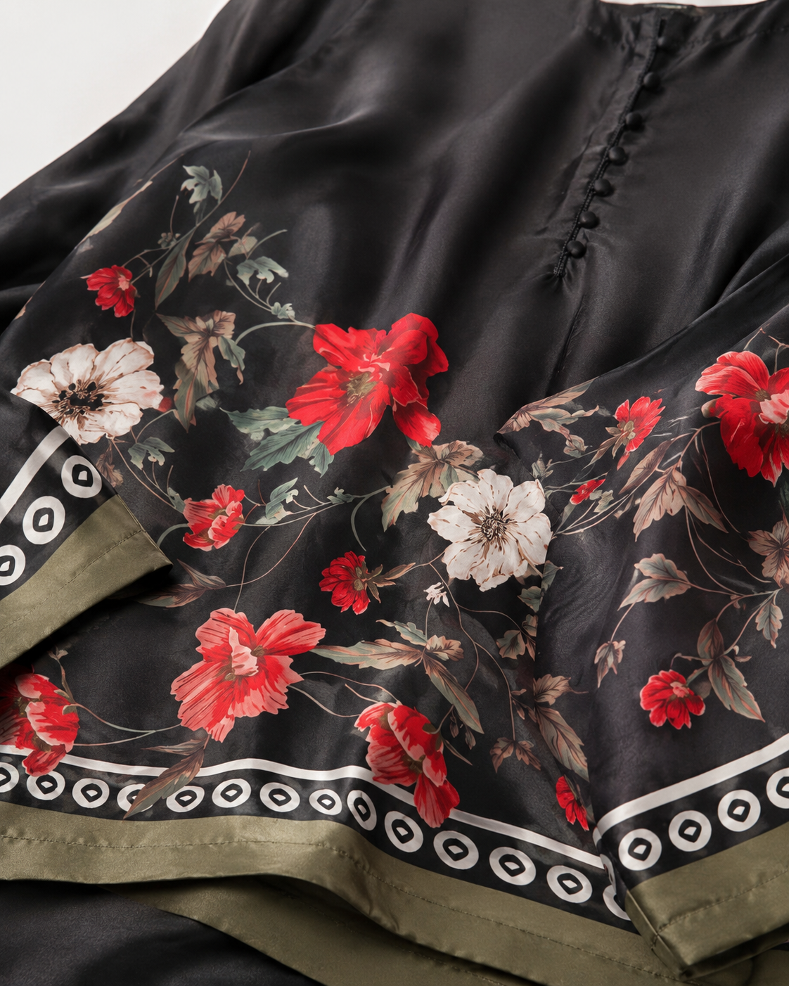 Close-up of the black satin-look floral fabric, decorative border and covered buttons of the BACTRA Gulzar Noir suit