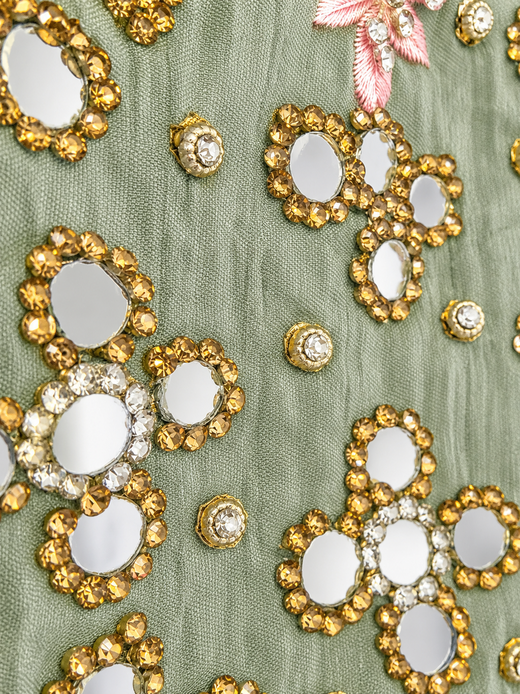 Close-up of sage green fabric with mirrorwork and pink embroidery